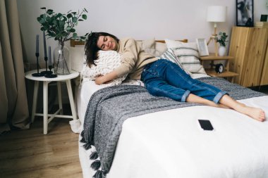 Haftasonu boyunca çıplak ayaklı, rahat bir yatakta, yastıklarla ve kapalı gözlerle uzanan İspanyol bir kadın vücudu.