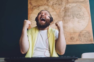 Kulaklıklı sakallı adamın elinde klavyeyle oturmuş bilgisayar oyunundaki başarısını yumruklarıyla kutluyordu.