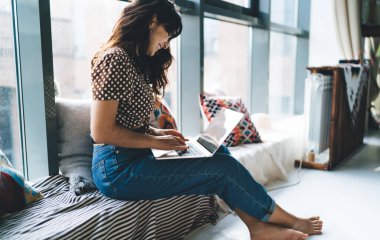 Genç heyecanlı kadın dizlerinin üstünde dizlerinin üzerinde dizlerinin üzerinde oturup internetten Webinar 'la çalışıyor. Uzaktan çalışan ve internet üzerinden alışveriş yapan mutlu kadın serbest yazar ağı