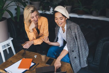 Laptop bilgisayarlı mutlu bayan meslektaşlar medya uygulaması üzerinden webinar videoları izliyorlar, Netbook ile neşeli serbest çalışanlar içerik yayınlarını okurken gülümsemek için 4G kablosuz bağlantıya geçiyorlar