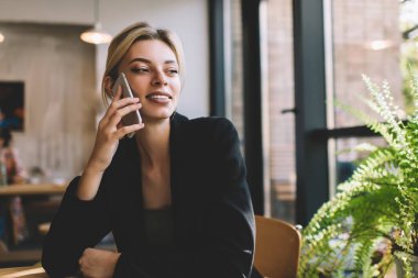 Başarılı bir kadın girişimci, akıllı ve rahat ceketli cep telefonu cihazıyla iş görüşmeleri hakkında konuşuyor ve arıyor, mutlu bir beyaz kadın hareket kabiliyeti iletişimini tartışırken telefonla konuşuyor.