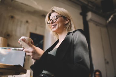 Klasik gözlüklü mutlu kadın blogcu sosyal ağlarda çevrimiçi mesajlaşmalarla eğleniyor, Kafkas kadın göz gezdirme web sitesinde kafeteryada 4 g internet bağlantısı kullanıyor.