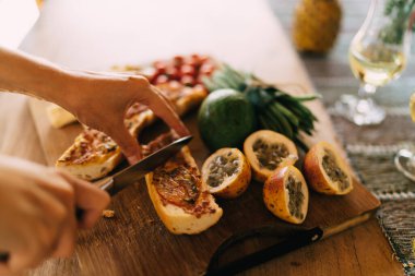 Tanınmayan bir kadın hafta sonunu kahvaltı hazırlamak için harcıyor. Kızarmış ekmekleri doğramak için. Karışık ve iştah açıcı olarak evde vejetaryen yemeği pişirirken sağlıklı yiyecekler kullanan kadınlar.