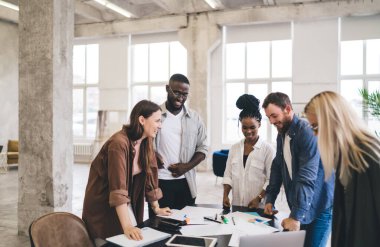 Genç ve yaratıcı çok ırklı iş arkadaşları, proje fikirlerini analiz etmek ve başlangıç stratejisi üzerinde çalışmak için masa başında toplandılar.