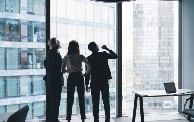 Resmi kıyafetlerle gökdelenlere bakan ve modern iş merkezinde çalışırken girişimi tartışan isimsiz çok ırklı iş adamlarının arka planı