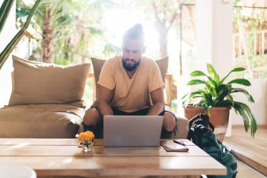 Ciddi bir erkek serbest yazar. Masada elinde akıllı telefon, kalem ve dizüstü bilgisayarla oturuyor. Ekrana bakıyor ve rahat otel odasındaki uzak bir projede çalışıyor.