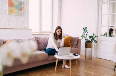 Doğum videolarına hazırlanırken bilgisayar başında oturup bilgi arayan konsantre bir kadın bebek bekliyor.