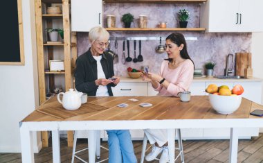 Masa başında kumar oynayan yaşlı ve etnik çeşitliliğe sahip kadınlar çay saatinde masada dinlenirken kumar oynuyorlar.