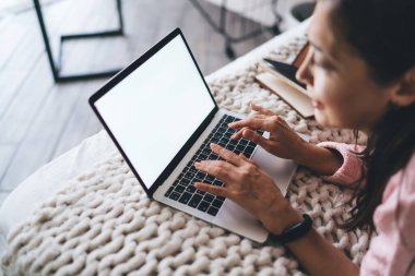 Tanımlanamayan bir kadının ekrana bakması ve rahat bir yatakta rahatlarken dizüstü bilgisayarda yazması ve evde video araması.