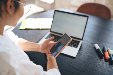 Beyaz gömlekli serbest çalışan, tahta masada oturan ve boş ekranla dizüstü bilgisayarda çalışan kadın.