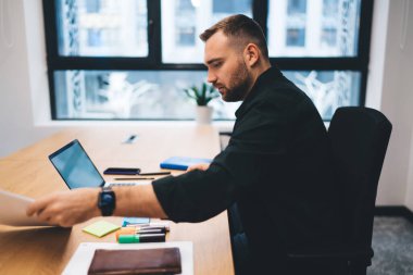 Adamın evrak işlerini yaparken bilgisayarını kullanırken yanında belge yapıştırıcı notlar ve sıkı çalışan bir defter vardı.