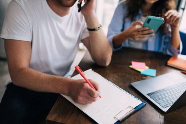 İsimsiz bir erkek cep telefonuyla konuşuyor ve tanınmayan bir kadınla otururken not alıyor. Proje üzerinde çalışırken ahşap masada dizüstü bilgisayarla ekranlara bakıyor ve akıllı telefonlara bakıyor.