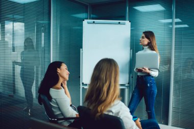 Modern ofiste başlangıç projesi stratejisi oluştururken, çok ırklı iş arkadaşlarıyla fikirlerini paylaşan kadın çalışanın düşük açısı