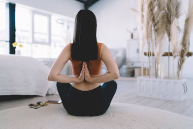 Modern apartman dairesinde yerde yoga yaparken Anjali Mudra 'yı ters çeviren formda bir kadın.