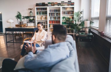 Randevu sırasında modern ofiste otururken not defteriyle durumu psikoloji danışmanına açıklayan isimsiz erkek müşterinin yan görüntüsü