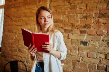 Modern kreatif kafeteryadaki tatilde defterdeki notlarla çalışırken, sarı saçlı, sırıtan bir kız öğrenci gözlerini kaçırıyor.