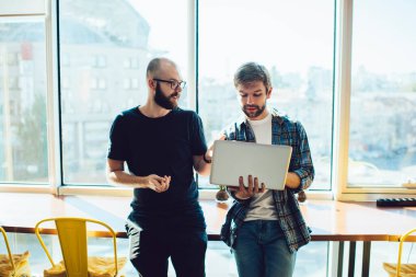 Portatif bilgisayarda iş projesine yatırım yapan konsantre erkek girişimciler ve modern çalışma alanında birlikte çalışırken kazançlarını kontrol edenler