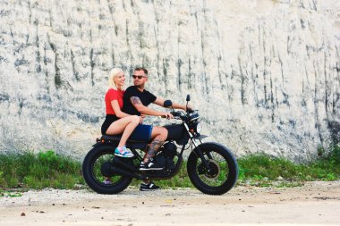 Romantik çift, yaz tatillerinde sarışın hippi kız arkadaşıyla gezintiye çıkan yakışıklı ve modaya uygun giyinmiş motorcu motosikletle birlikte boş zaman geçirmekten hoşlanıyor.