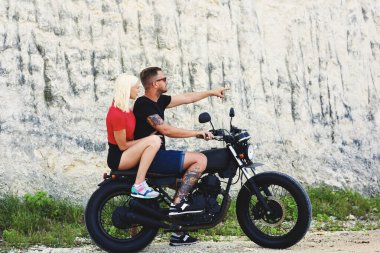 Dövmeli, güneş gözlüklü, güzel sarışın kız arkadaşıyla gezen yakışıklı bir motorcu. Yaz tatilini motosiklet macerası yaşayarak geçiren bir çift.