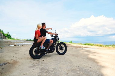 Romantik aşık bir çift ve yaz tatillerinde motosiklet yolculuğunda güzel doğal manzara. Erkek hippi Skyline 'ı işaret ediyor. Sarışın kız arkadaşıyla birlikte. 