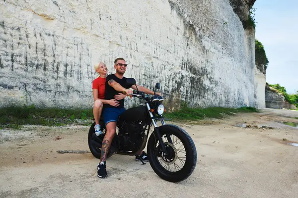 Mutlu, aşık genç çift hafta sonlarını birlikte geçirmekten memnun, güneş gözlüklü yakışıklı erkek bisikletçi çekici sarışın kız arkadaşıyla motosiklet sürüyor.