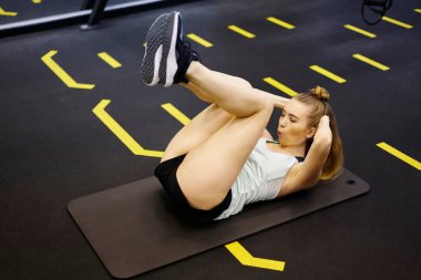 Beden eğitiminde ağız havası üflerken karın kasları ve çatırtı egzersizleri yapan genç ve formda bayan sporcuların yan görüntüsü.