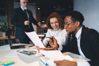 Bir grup mutlu iş adamı resmi giysiler içinde masada oturup evrak okurken aynı zamanda ofiste yeni bir iş kurma araştırması yapıyorlar.