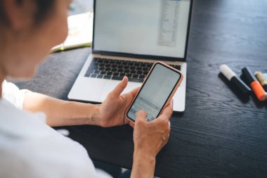 Beyaz tişörtlü, yüzü olmayan, iş yerinde telefon kullanan, netbook mesajlaşması yapan ve uzaktan çalışan bir kadından.