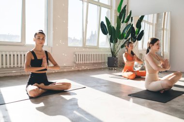 İnce kadın sporculardan oluşan vücut, yoga kursunda nilüferlik ve dinlenme egzersizleri yaparken meditasyon yapan ve gülümseyen.