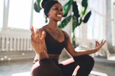 Gyan Mudra Afro-Amerikan kadınlarının hafif odak noktası gülümseyip yerde otururken ve evde Padmasana 'da meditasyon yaparken.