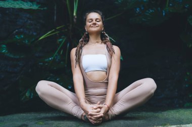 Sabah hatha yogası sırasında iç huzuru hisseden sakin eşofmanlı kadın doğa enerjisini elde etmek için kaygısız kadın dışarıda bütünsel meditasyon sırasında zevk ve farkındalığın bolluğundan zevk alıyor.