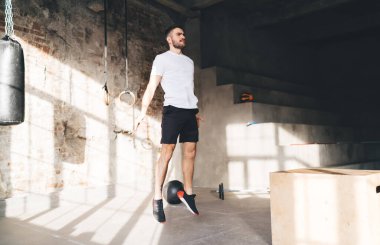 Modern spor salonunda spor yaparken ve spor yaparken spor yaparken elleri açık atlayan erkek sporcu.