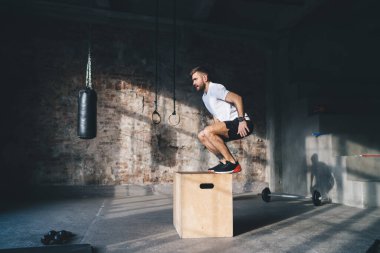 Spor salonunda spor yaparken ve antrenman yaparken spor salonunda atlayan aktif giyimli güçlü erkek sporcuların vücut tarafı.