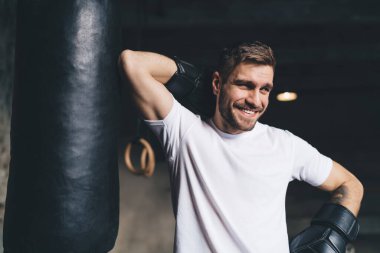 Güler yüzlü, sakallı boksör boks eldivenleri giymiş, spor salonunda antrenman yaparken kafasını çevirmiş.