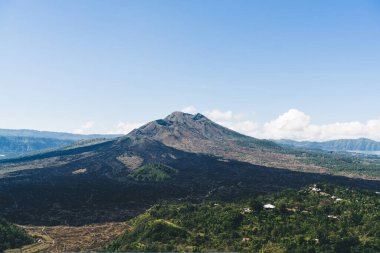 Güneşli bir günde, mavi gökyüzünün altında yeşil ağaçlarla kaplı gökyüzü manzaralı gökyüzünden vadiye uzanan görünmeyen yol boyunca uzanan binalar ve uzak göle ulaşıyor.