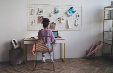 Genç milenyum kadın bilgisayar cihazıyla evde oturup uzaktan kumandayla çalışıyor. Webinar kursuyla çevrimiçi öğrenen kız öğrenci uzaktan çalışmak için taşınabilir netbook kullanıyor