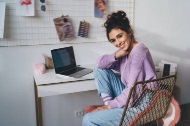 Genç milenyum kadın bilgisayar cihazıyla evde oturup uzaktan kumandayla çalışıyor. Webinar kursuyla çevrimiçi öğrenen kız öğrenci uzaktan çalışmak için taşınabilir netbook kullanıyor