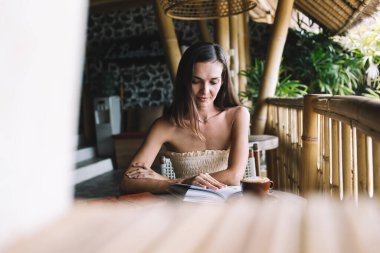 Bir fincan sıcak içecekle odaklanmış serbest çalışan kadın ve kahve evindeki proje üzerinde çalışırken verileri analiz eden organizatör.