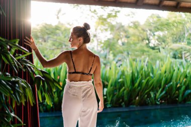 Güneş banyosu yapan ve yaz sabahları tropikal tatil beldelerinde yüzme havuzunun yanındaki manzaranın tadını çıkaran kadın turistlerin arka planı.