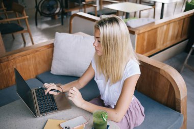 Kafede boş zamanlarında sosyal ağlarda web sayfasını taramak için dizüstü bilgisayarda 4G kablosuz internet sitesine bağlanan yetenekli bir kadın blog yazarı, yayıncılık metni okuyan Kafkasyalı genç hippi kız