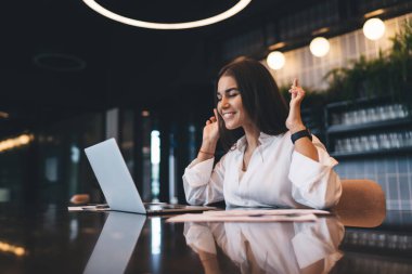 Beyaz gömlekli genç bayan işçi, modern kafede uzaktan çalışan yeni serbest çalışma projesiyle ilgili iyi haberler almayı umarak parmaklarını çaprazlıyor.