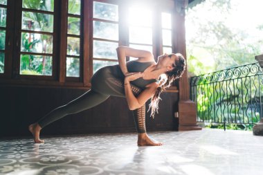 Twisted Utkatasana yoga poz veren esnek bayan sporcu Anjali Mudra 'nın elleri ile tropik tatil beldesinde