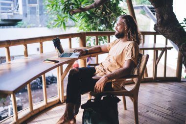 Uzun saçlı yazılım geliştirici çevrimiçi veri programlama için dizüstü bilgisayar uygulaması kullanıyor, yetenekli erkek bilişim uzmanı terasta kablosuz tarayıcı ağı kurmak için dijital netbook üzerine medya uygulaması yüklüyor