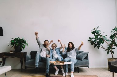 Evde birlikte eğlenirken kanepede pizza yiyip gülen iyimser ailelerin tüm vücudu.