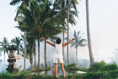 Arkadan bakıldığında, sıradan giysiler içinde, kollarını açmış Bali 'de özgürlüğün tadını çıkartan kimliği belirsiz bir erkek görülüyor.