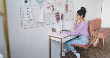 Genç milenyum kadın bilgisayar cihazıyla evde oturup uzaktan kumandayla çalışıyor. Webinar kursuyla çevrimiçi öğrenen kız öğrenci uzaktan çalışmak için taşınabilir netbook kullanıyor