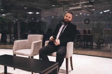 Tam vücut pozitifti. Resmi giysiler içinde, koltukta dinleniyor ve modern ofis binasının molasında kameraya bakıyordu.