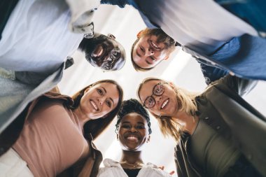 İçerideki odada el ele tutuşup kameraya bakarken gülümseyen, çoklu etnik çeşitlilikte neşeli meslektaşlardan oluşan bir grubun içinden.