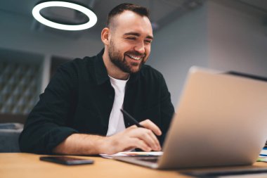 Düşük açılı, günlük kıyafetli, netbook kullanarak masada oturan, ofiste çalışırken internet üzerinden iletişim kuran,