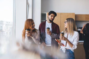 Bir grup genç meslektaşım, tatilde konuşurken ve bakarken kağıttan bardaklardan kahve içerken ofisin bulanık ön camında dikiliyorlar.